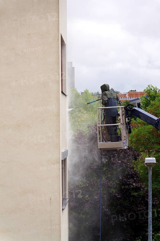 Unrecognizable man cleaning facade surface from lifting platform with high pressure stream of water Prague, Czech republic