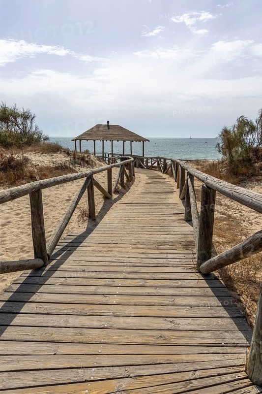 A wooden walkway leads to a cabin by the sea. View of the Atlantic Ocean from the beach of the Pinar de la Almadraba Nature Reserve, Pinares De Rota, Rota, Cadiz, Andalucia, Spain