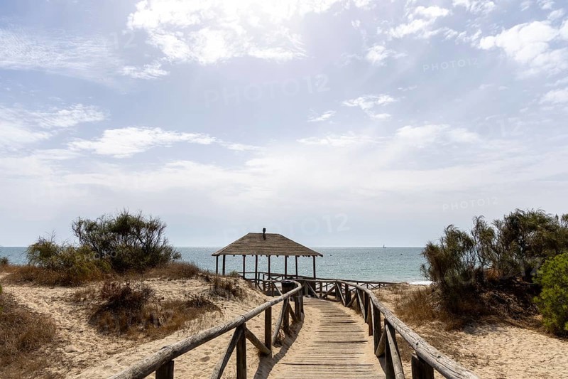 A wooden walkway leads to a cabin by the sea. View of the Atlantic Ocean from the beach of the Pinar de la Almadraba Nature Reserve, Pinares De Rota, Rota, Cadiz, Andalucia, Spain