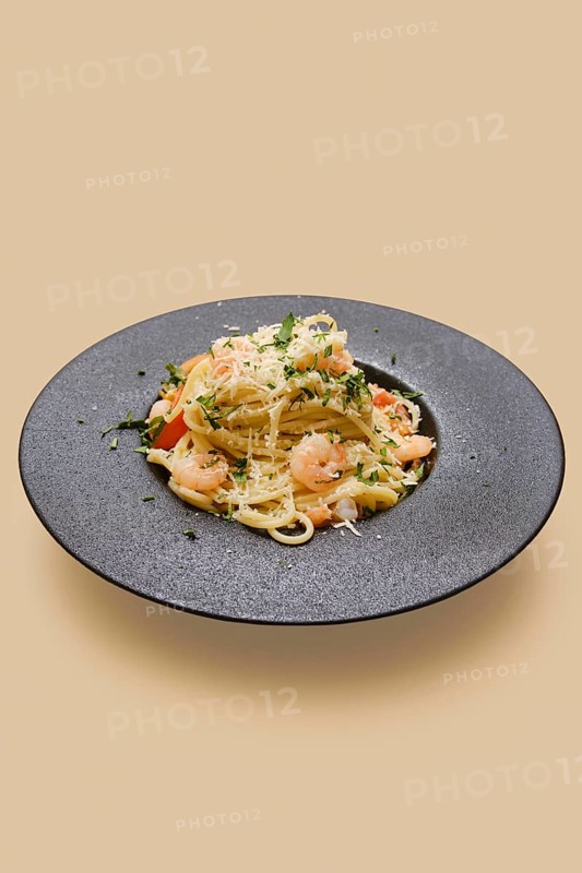 Delicious creamy garlic shrimp pasta rests artfully on a dark plate. The pasta showcases tender shrimp, fresh herbs, and a rich sauce, making it a perfect meal for any occasion