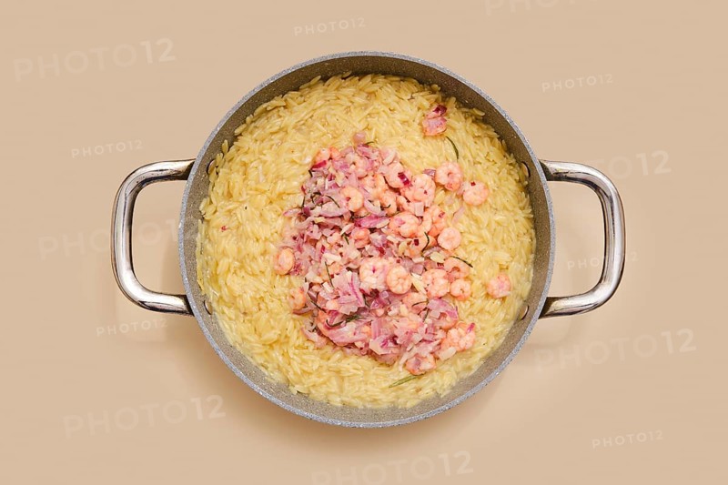 A pot with cooked risoni pasta and fresh shrimps. The dish features a creamy texture and vibrant colours. Ideal for a quick, satisfying meal at home
