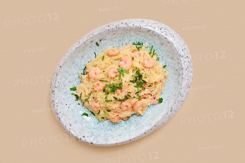A delightful dish features risoni pasta mixed with tender shrimp and sprinkled with fresh herbs. This meal is perfect for a comforting lunch or dinner, showcasing simplicity and flavor