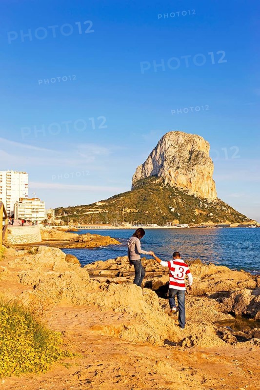 Two people on a rocky coast, natural park, in the background rock Penon de Ifach, landmark, Mediterranean Sea, Calpe, Valencia, Costa Blanca, Spain