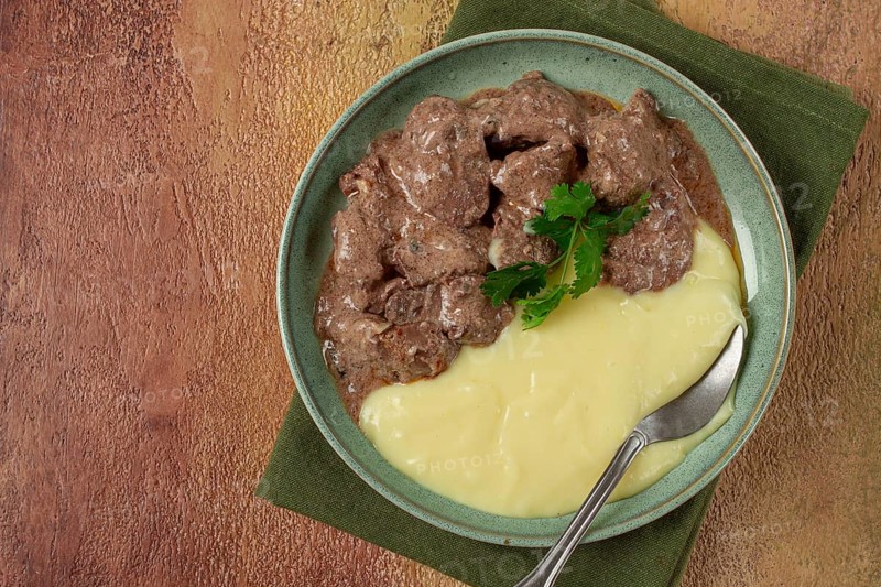 Liver beef stroganoff with mashed potatoes, table setting in green tones, homemade
