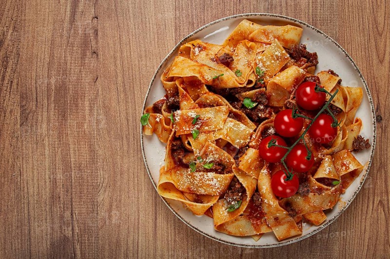 Pappardelle pasta with bolognese sauce, topped with parmesan cheese and cherry branch, homemade, no people