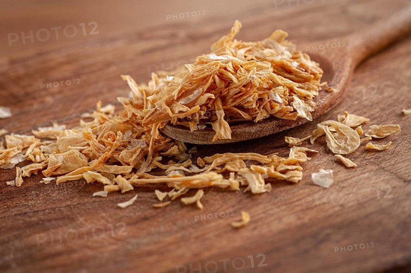 Smoked onion flakes, on a wooden spoon, wooden table, close-up