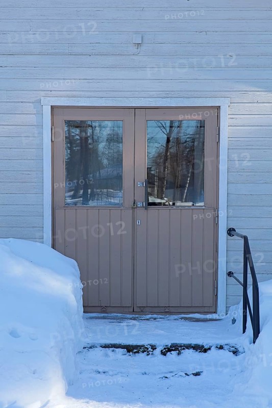 Double doors and steps on a old wood building in winter with snow on the ground, Vastila, Finland
