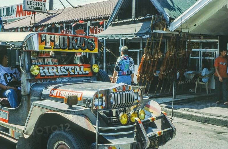Jeepney minibus in front of a restaurant with skewered suckling pig, Lechon, Manila in 1995, Philippines