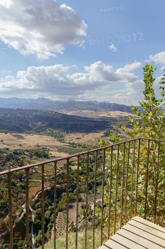 Ronda, malaga, spain Viewpoint balcony overlooking the vast valley with mountains and fields under a blue sky with clouds in ronda, andalusia