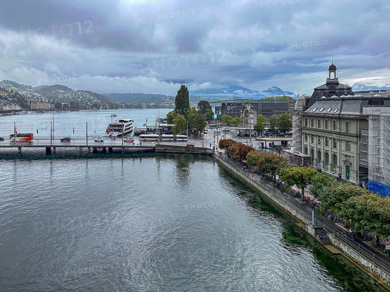 View of waterfront with boats and mountains in the background under cloudy sky, Lucerne, Switzerland