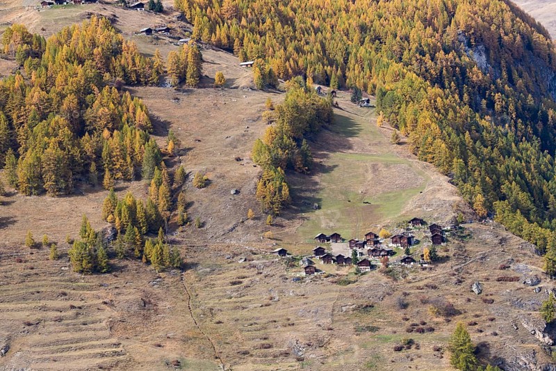 Tiny little town on the mountain. Wooden nostalgic houses are surrounded by grassland and forest in autumn colours. Rhone Valley, Valais, Switzerland