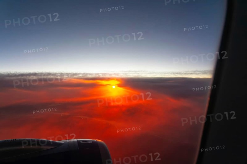 Sunrise through clouds seen from plane window