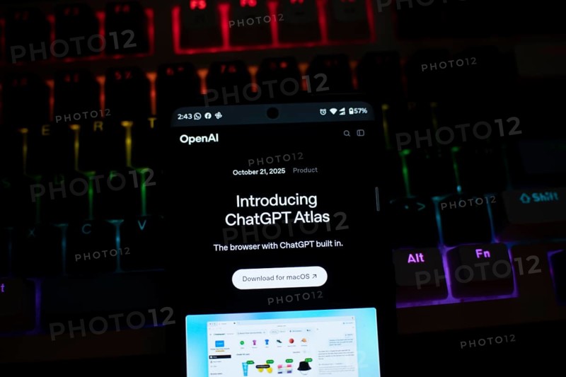 A smartphone displaying ChatGPT Atlas against a colorful, illuminated keyboard