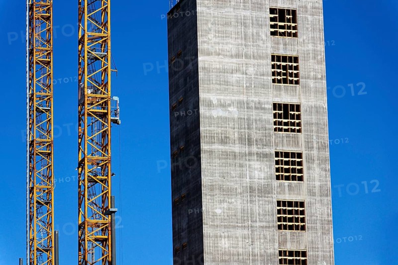Two yellow cranes on skyscraper construction site of timber building Kaj 16 with hybrid concrete frames, sunny day, Lilla Bommen area, Gothenburg, Sweden