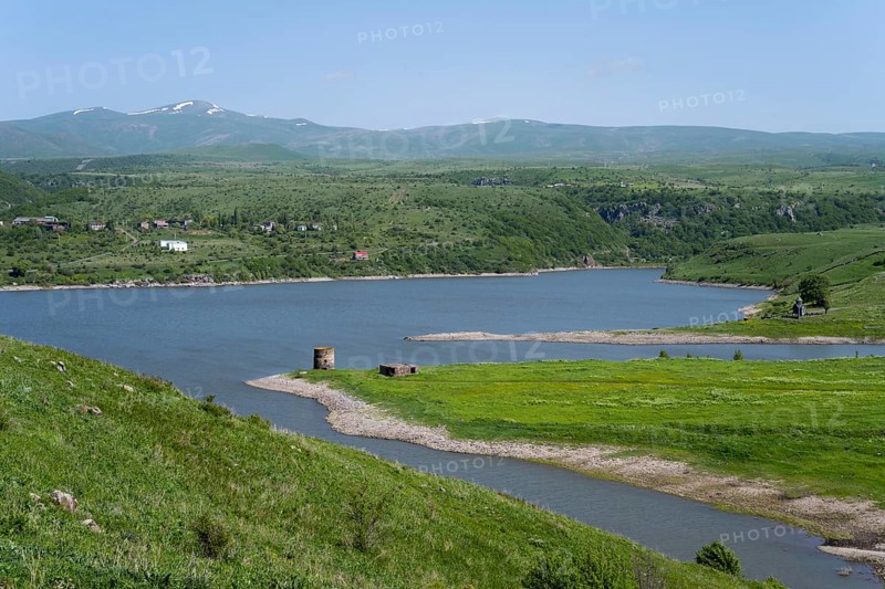 Winding river flows into a lake surrounded by green hills under a blue sky, Kechut Reservoir, Kushchi, Kush-Bilyak, Wajoz Dzor Province, Vayots Dzor, Armenia