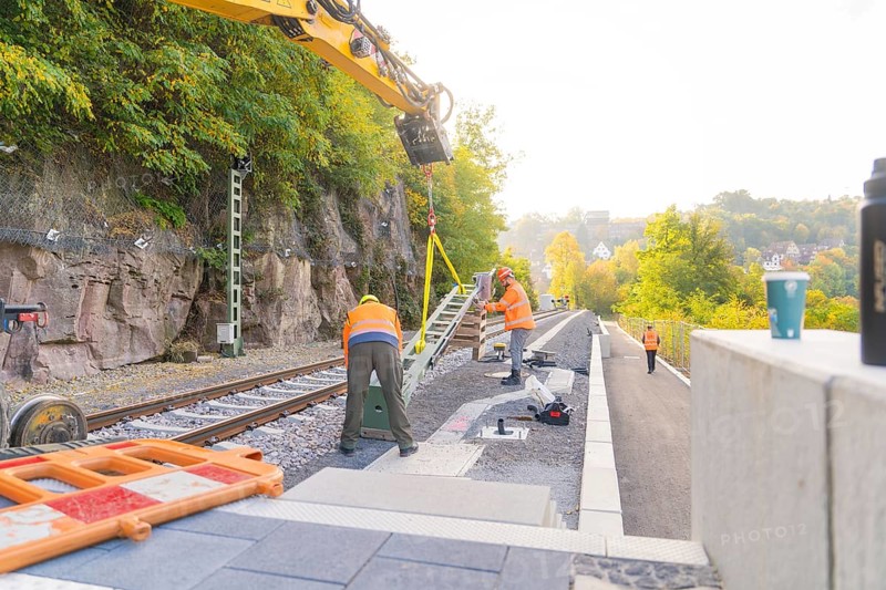 Worker with excavator on railroad tracks, autumnal atmosphere, signal construction at the Hermann Hessebahn, Calw, Germany