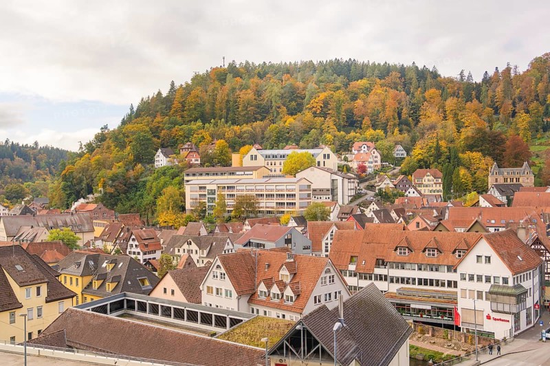 Village on a hill with half-timbered houses and wooded slopes in autumn, Calw, Black Forest, Germany