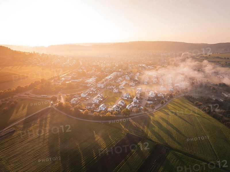 A small town surrounded by fields at sunrise with enchanting fog, Calw Stammheim, Black Forest, Germany