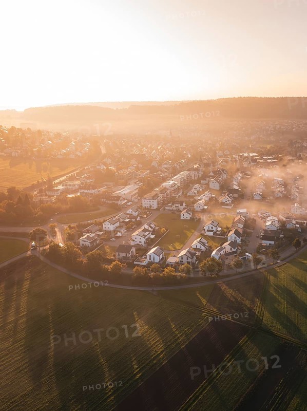 Village and fields in morning fog with warm shades of sunrise light, Calw Stammheim, Black Forest, Germany