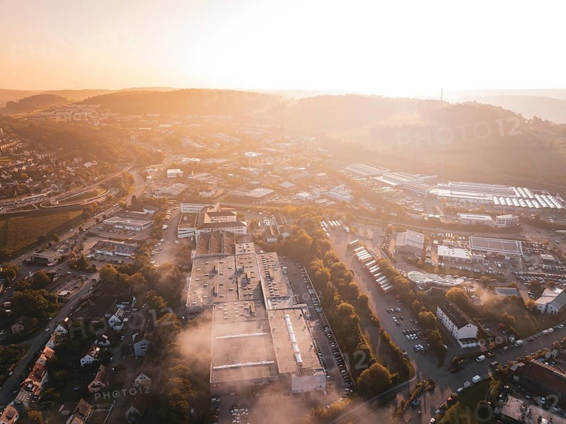 Aerial view of an industrial urban area and fields in orange morning fog, Calw Stammheim, Black Forest, Germany