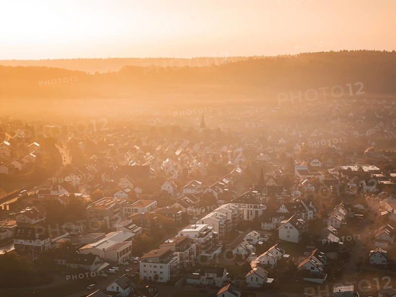 Aerial view of a village in morning fog at sunrise with warm orange light, Calw Stammheim, Black Forest, Germany