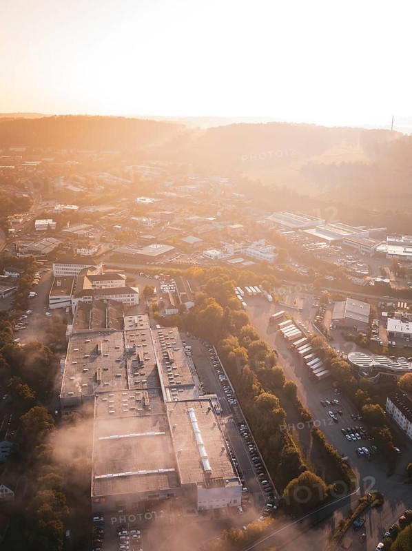 Urban industrial area in morning fog illuminated by warm sunlight, Calw Stammheim, Black Forest, Germany
