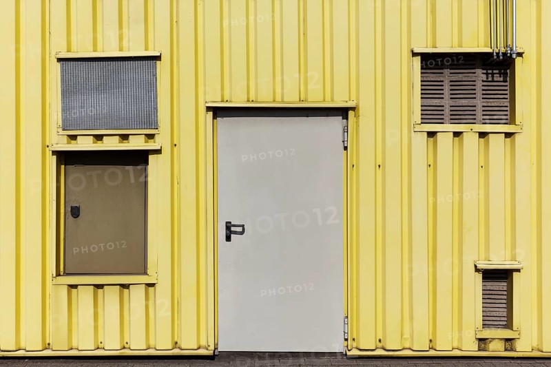 Yellow profiled sheet façade of an industrial building, doors and openings with ventilation grilles, Düsseldorf, North Rhine-Westphalia, Germany