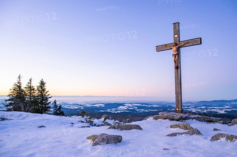 Christian cross on the peak of Mount Lusen with the view over the hills of the bavarian forest at sunrise at winter, Bavaria, Germany