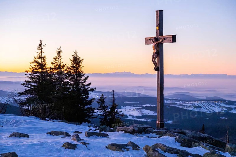 Christian cross on the peak of Mount Lusen with the view over the hills of the bavarian forest at sunrise at winter, Bavaria, Germany