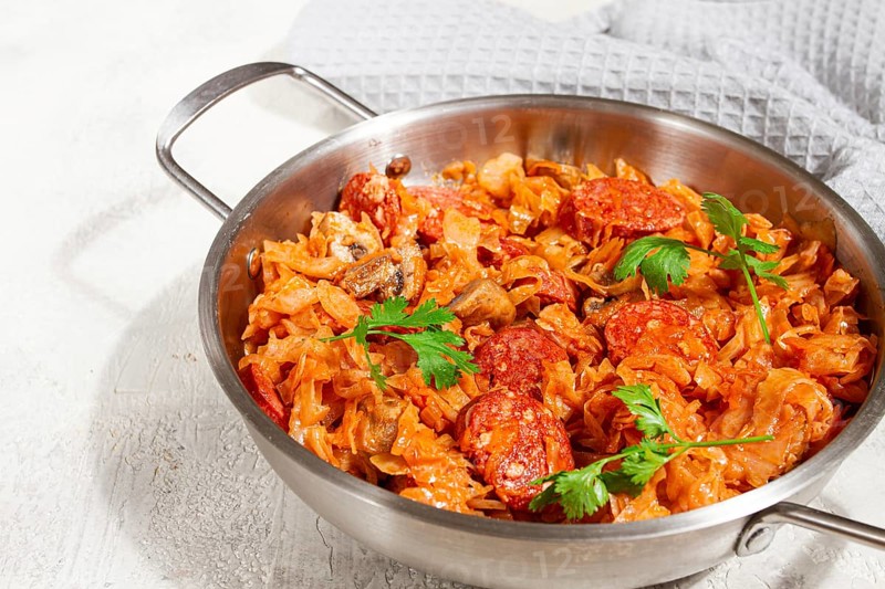 Polish dish bigos, in a stainless steel pan, stewed meat with cabbage, chorizo sausages, mushrooms, homemade, without people