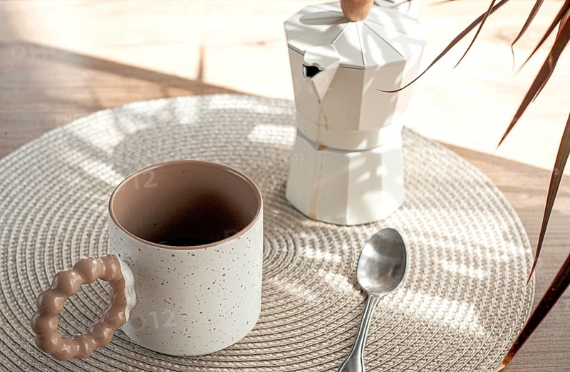 Making morning coffee, geyser coffee maker and mug, in bed colors, on a wooden table, natural light, no people