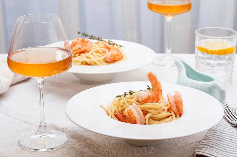 Pasta with shrimp and thyme, served on a white plate, with a glass of white wine, the table is set, Gourmet dinner, on a linen tablecloth, no people