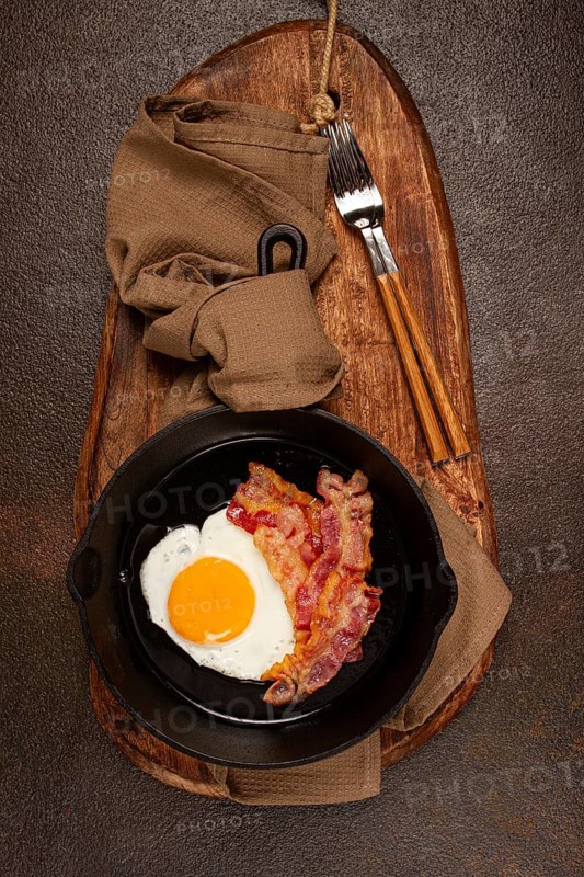 Fried egg with bacon, in a cast-iron pan, breakfast, top view, close-up, homemade, no people