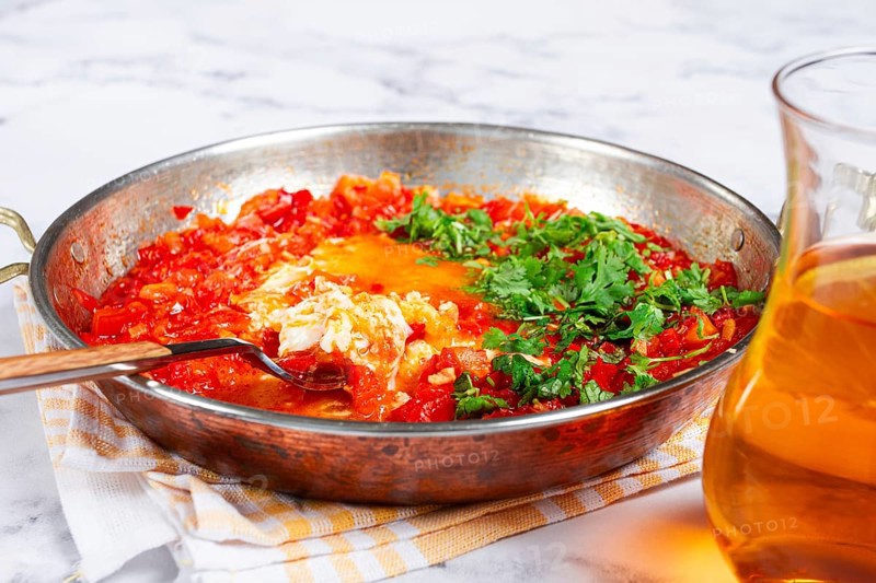 Traditional Turkish dish, scrambled eggs with tomatoes, Menemen, with herbs, in a frying pan, close-up, no people