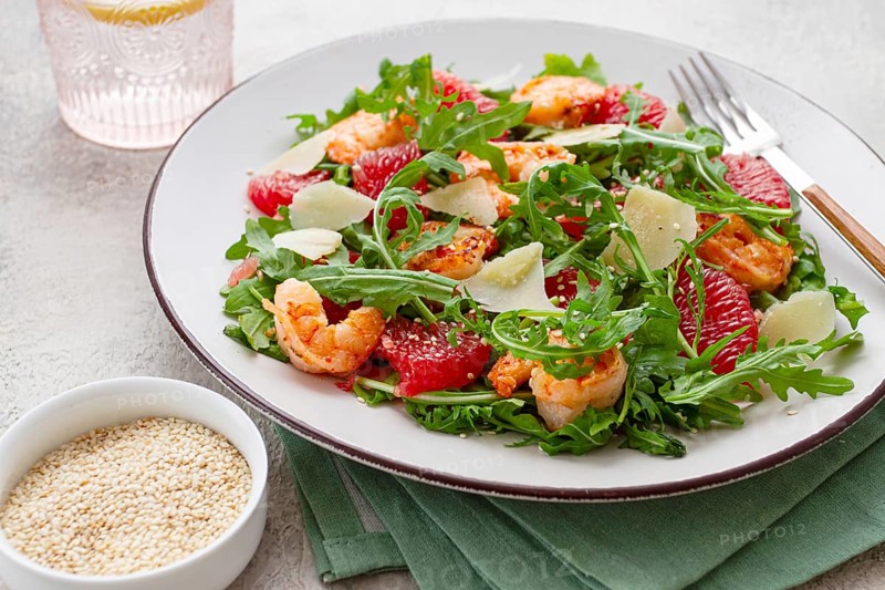 Fresh shrimp salad with arugula, grapefruit, and parmesan served in a bowl
