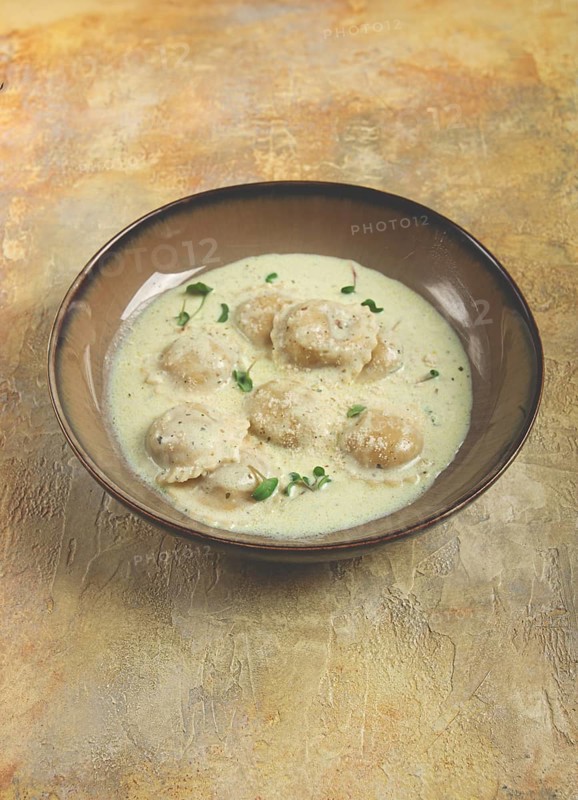 Ravioli in cream sauce, spices and herbs, top view, no people