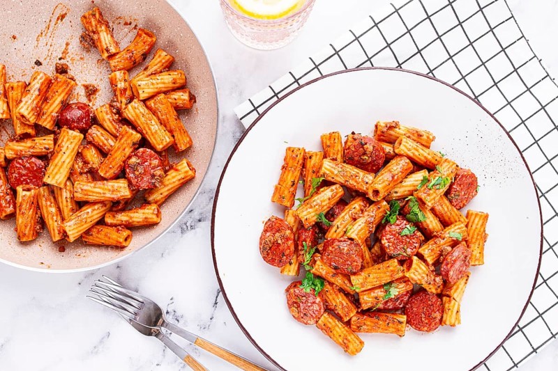 Rigatoni pasta with spicy sausage, and rich tomato sauce served, on a white plate, homemade