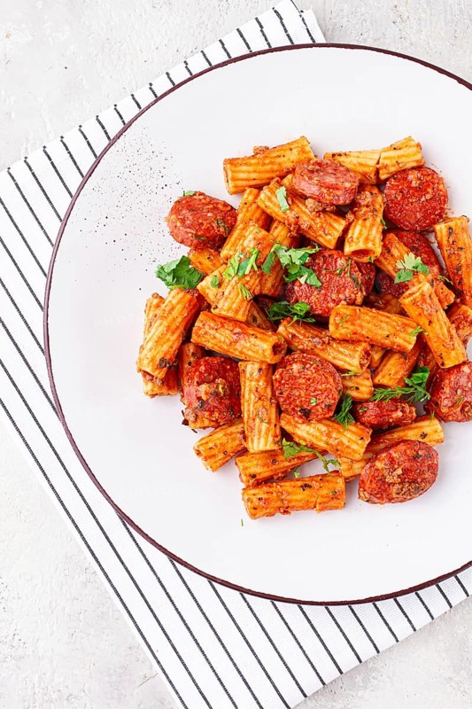 Rigatoni pasta with spicy sausage, and rich tomato sauce served, on a white plate, homemade