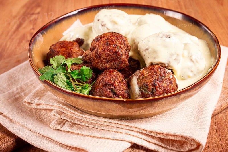 Swedish meatballs in cream sauce, plate on a wooden table, homemade, no people