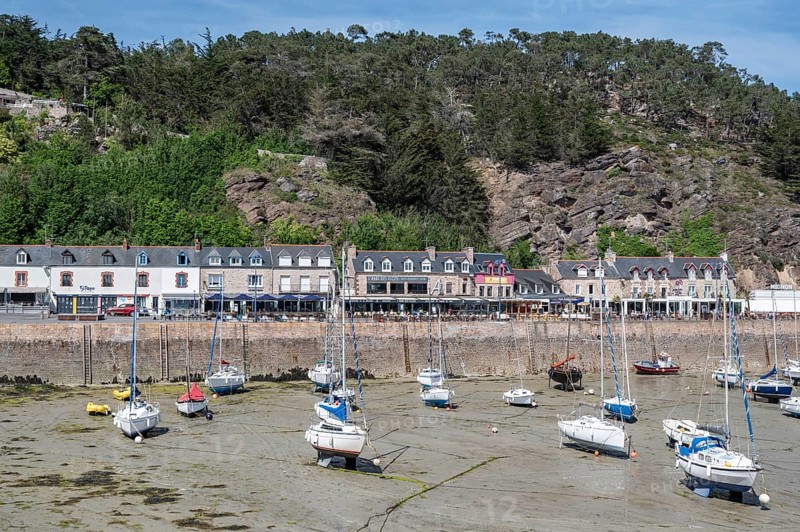 View of Erquy Bay at low tide with a fortified promenade behind which a series of bright, multi-storey residential buildings extend along Rue du Port, Erquy, Saint-Brieuc Bay, Côtes-d'Armor, Brittany region, France