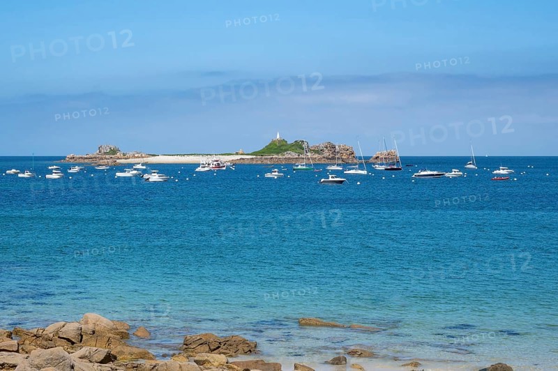 In the turquoise-blue waters of the English Channel, motor boats and sailboats anchor off small, rocky islands Sport Blanc, Penvenan, Cotes-d'Armor, Brittany region, France
