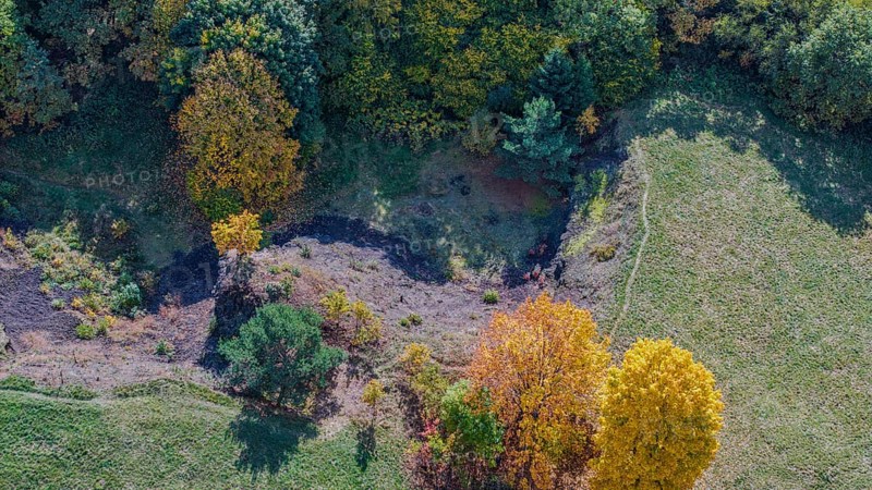In a rural area, the scenery shows colorful autumn trees near an extinct volcano. The colors vary from yellow to orange and green. Železná hurka, Czech Republic