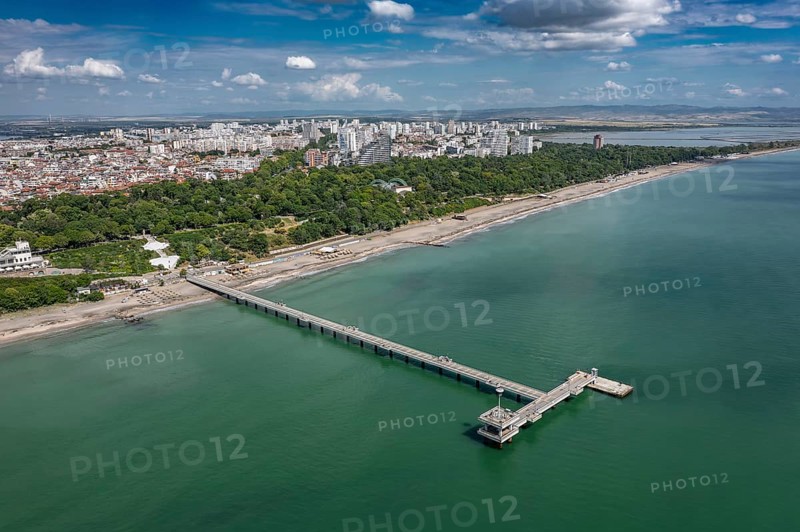 Aerial view of a long pier extending into the sea with cityscape in the background. Aerial view to bridge in the sea in Burgas, Bulgaria