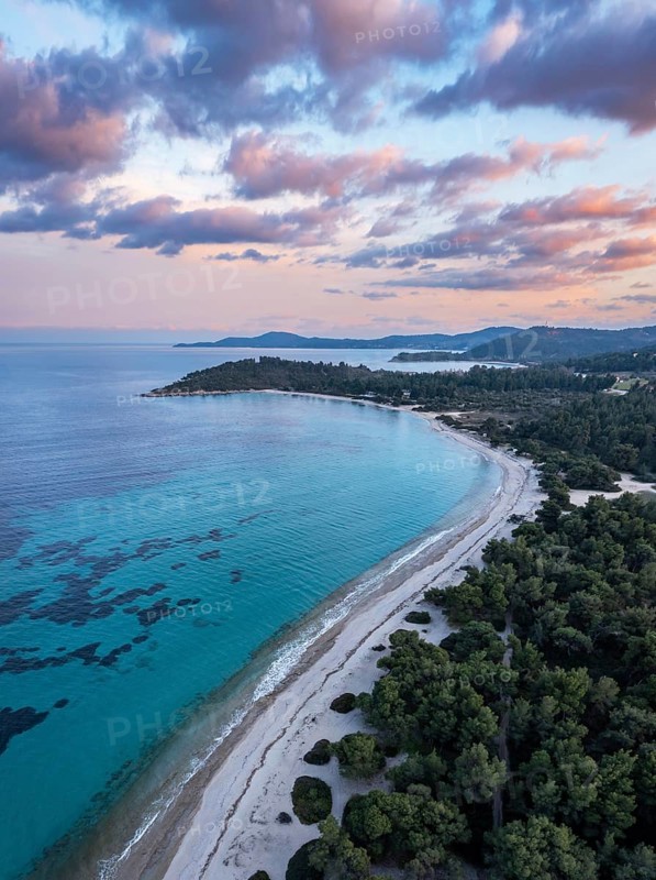Aerial view of a beach and coastal forest with a peaceful sea at sunset. Aerial view of Glarokavos beach in Kassandra peninsula. Chalkidiki, Greece