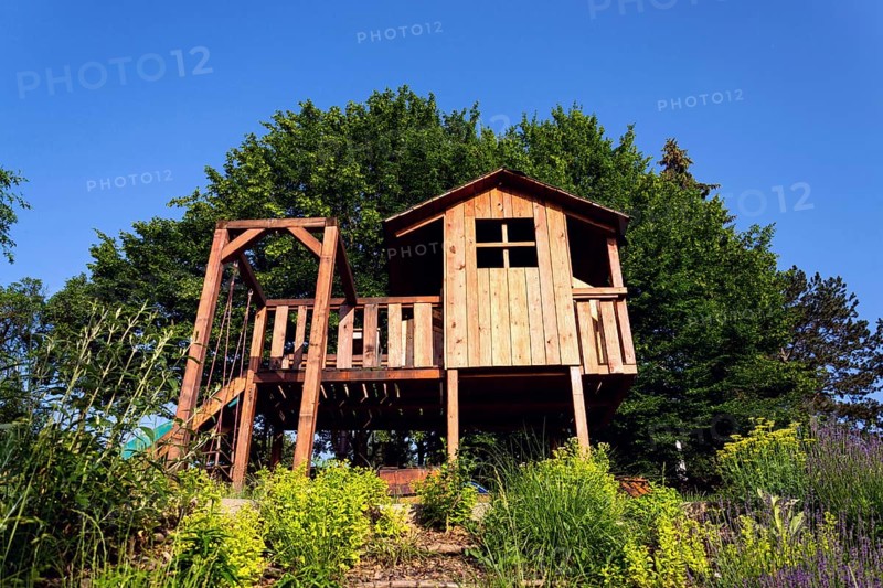Beautiful wooden children playhouse with swing and slide on hillside Krivoklat Czech republic