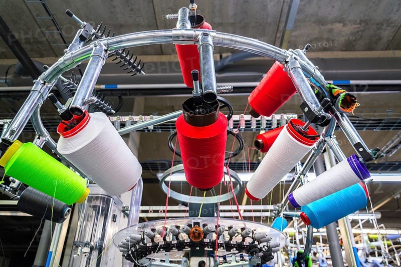 Colorful reel thread set up at modern and automatic sewing or embroidery spinning machine, textile industry factory concept Prague Czech republic