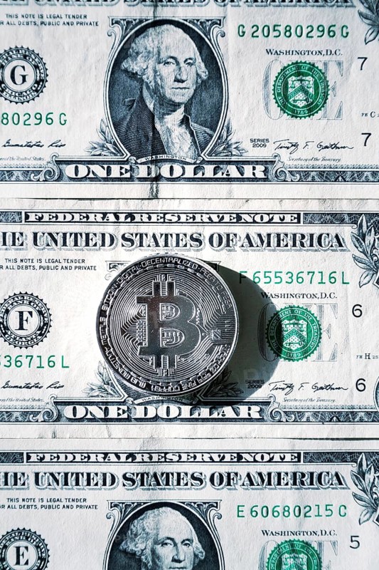 Silver bitcoin coin lying on United States dollars, cryptocurrency concept Prague Czech republic
