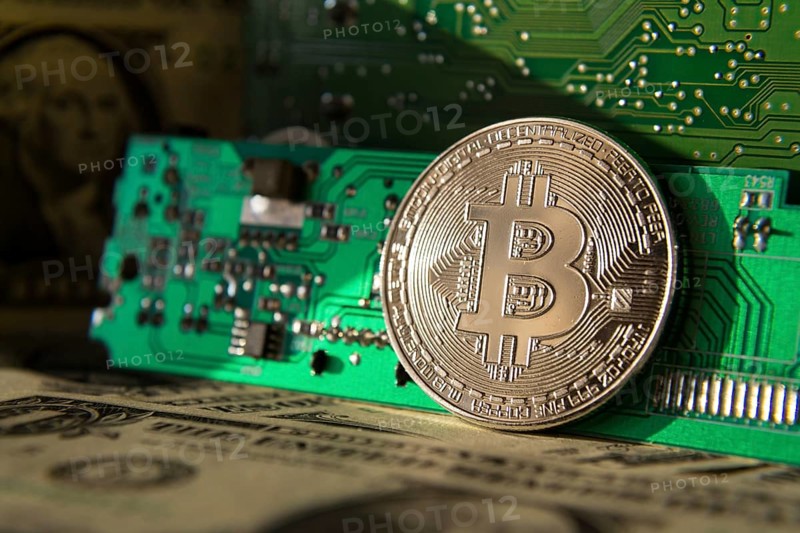 Silver bitcoin coin with dollars and computer motherboard, cryptocurrency mining and investing concept Prague Czech republic