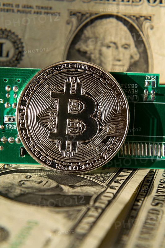 Silver bitcoin coin with dollars and computer motherboard, cryptocurrency mining and investing concept Prague Czech republic