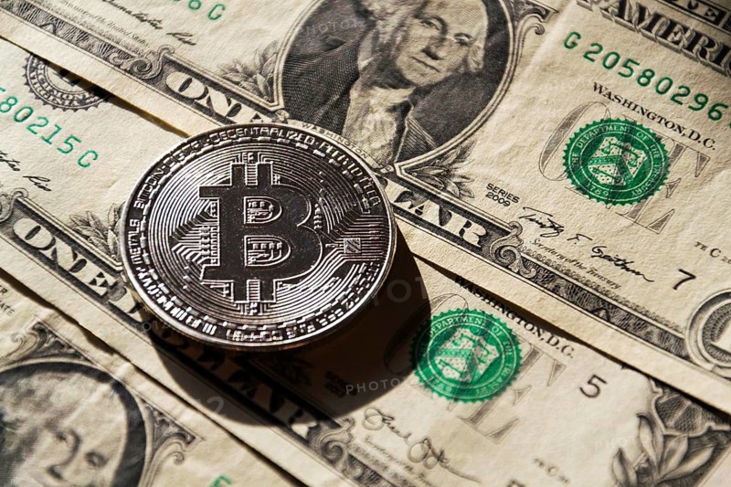 Silver bitcoin coin lying on United States dollars, cryptocurrency concept Prague Czech republic